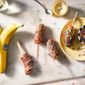 Bevroren bananenpops met een laagje chocolade en (gekleurde) hagelslag